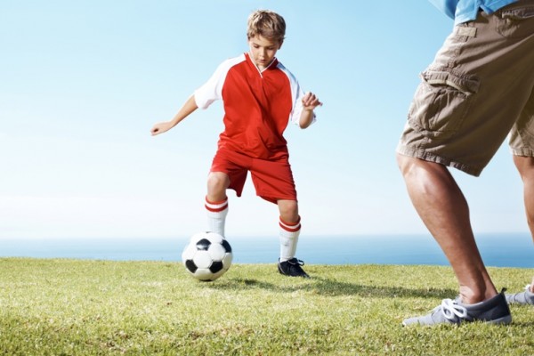 Small boy playing a soccer game with a man