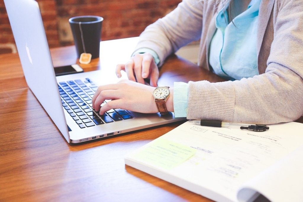 Person filling out online application on desk